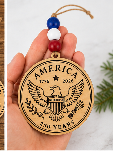 Handcrafted wooden America 250 ornament featuring Eagle. Laser engraved patriotic keepsake with red, white, and blue bead accents celebrating America's 250th anniversary.